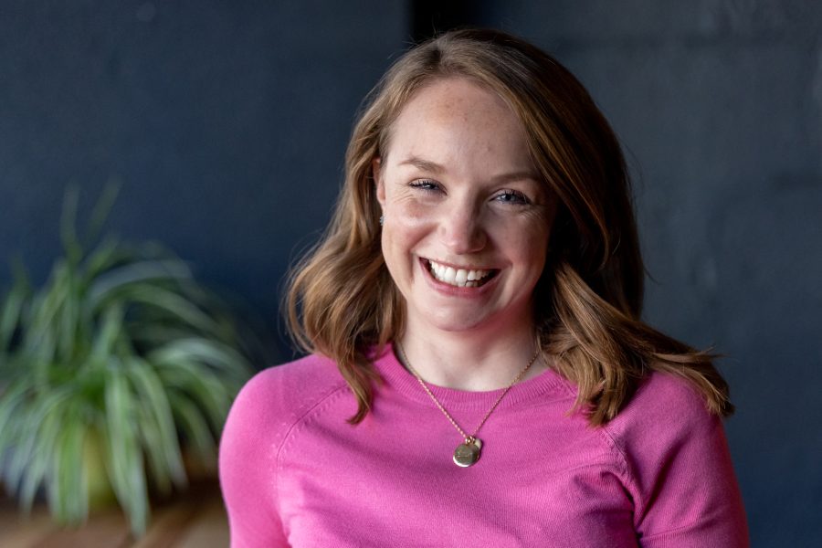 Maddie Pinkham, brown hair pink jumper with neckless in office setting