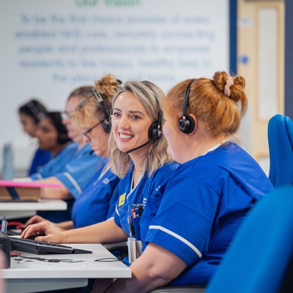 Blue Lozenge healthcare communications expertise supporting NHS trusts and health organizations with strategic messaging and engagement NHS healthcare staff in blue scrubs wearing headsets working at call center with vision statement on wall. digital care hub