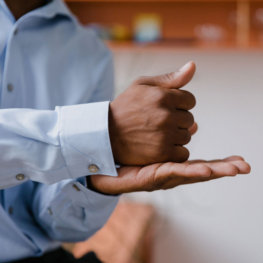 A man using sign language indoors with a focus on hand gestures and communication.