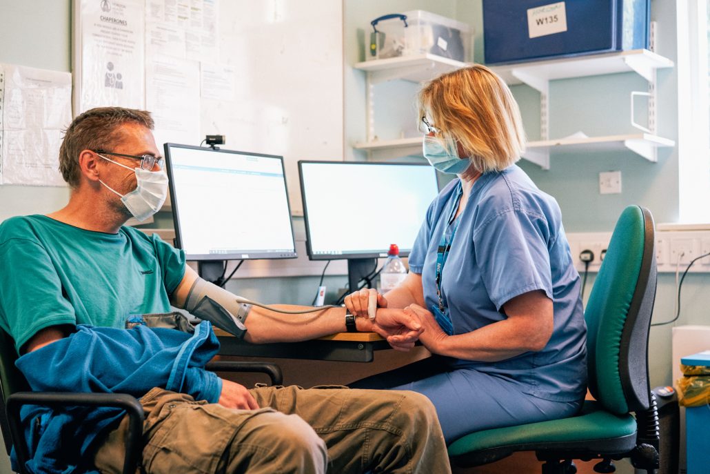 A nurse measures a patient's blood pressure using a sphygmomanometer in a clinical setting.