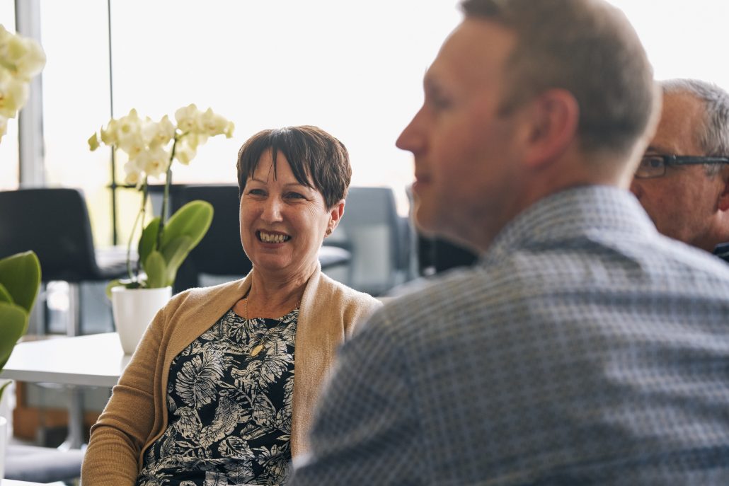 A woman and a man engaged in conversation in a modern office setting.